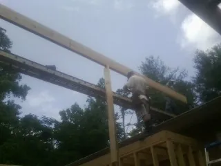 Carpenter setting a ridge beam over a new addition frame — Ice Dam Removal by Roofing Brothers in Onley