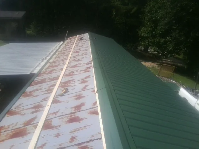 Old rusted panels beside newly installed green metal roofing — Wind Damage Roof Repair by Roofing Brothers in Onley