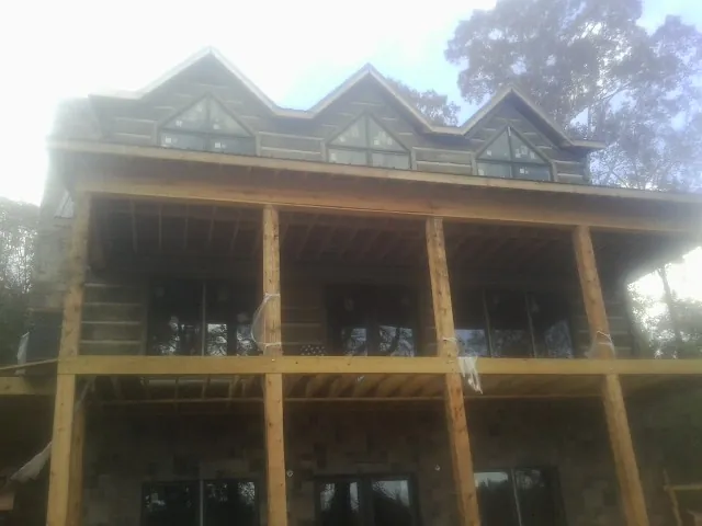 Dormers and porch framing on a large log home under construction — Roof Coating work by our crew in Onley