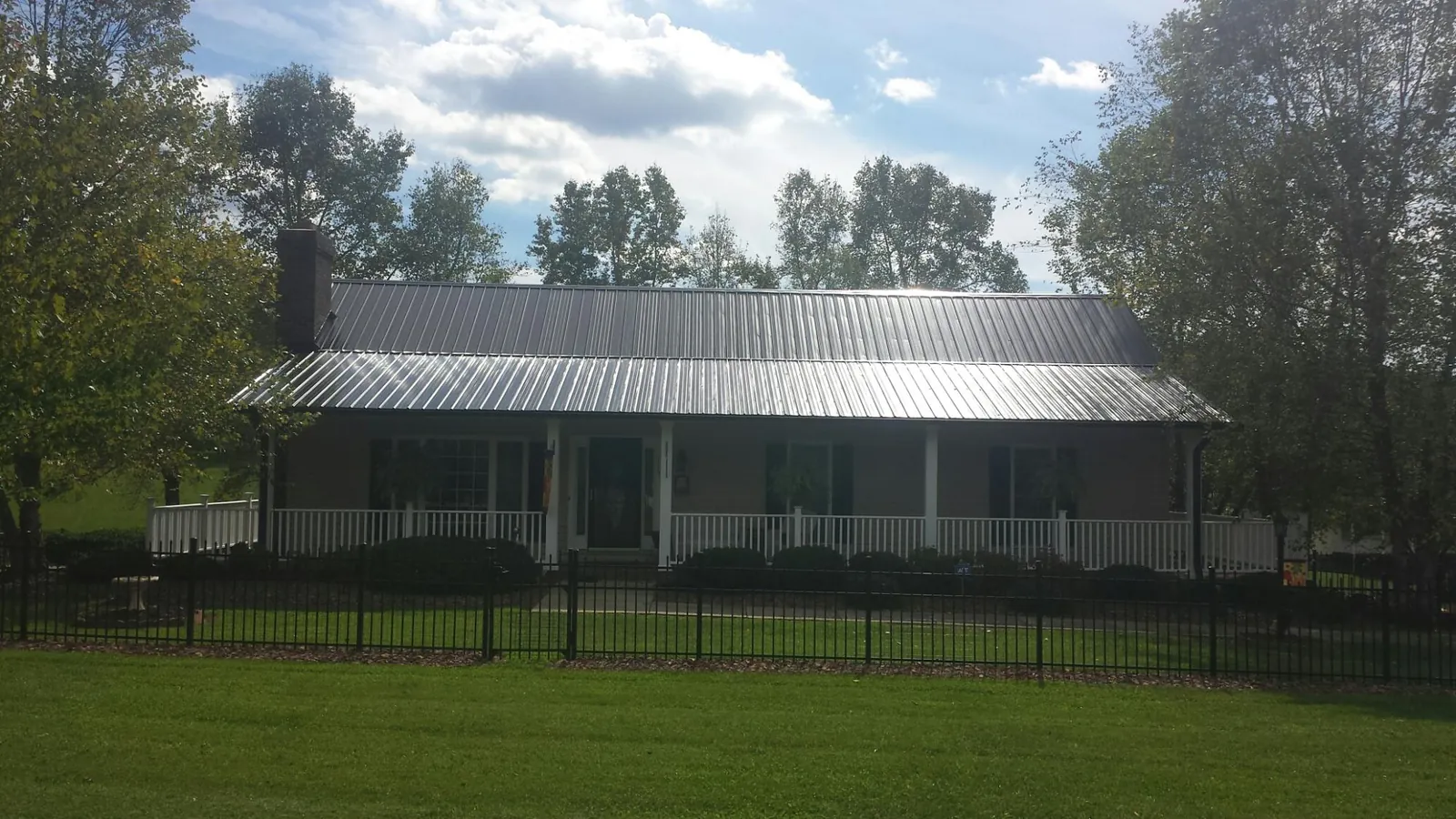 Gray metal roof on a brick ranch with a full width front porch — Gutter Guard Installation work by our crew in Onley