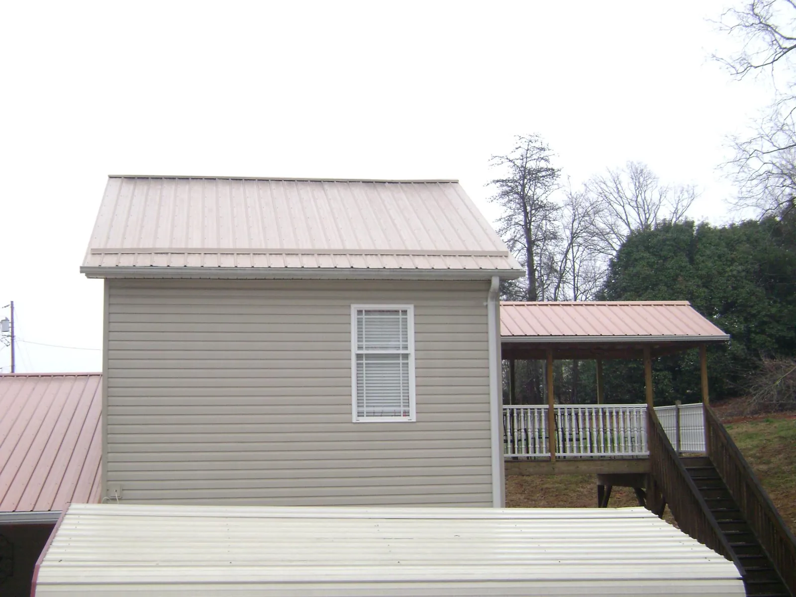 Tan metal roofs on a two story addition and attached porch, from a Roof Replacement job in Onley