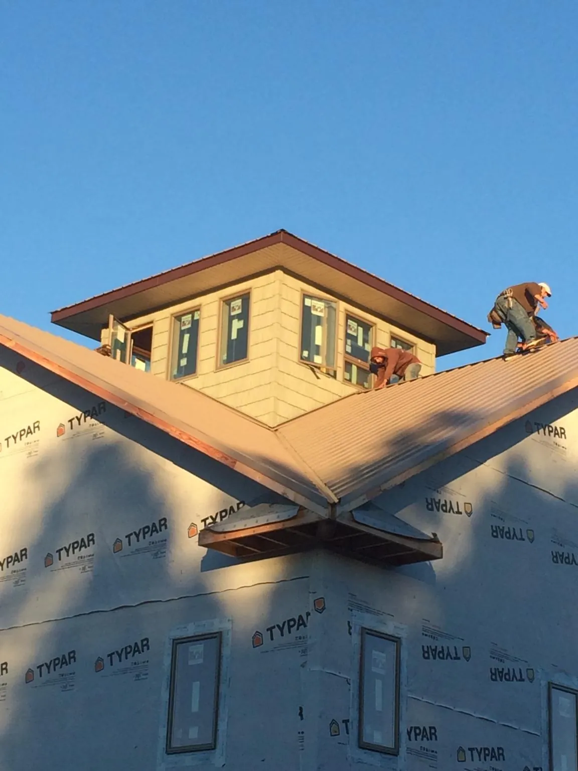 Roofers working around a rooftop cupola on a new metal roof at sunset — Roof Waterproofing in Onley by Roofing Brothers